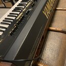 Černý elektronický klavír s bílými a černými klávesami. Na pravé straně je žlutý nápis YAMAHA a v horní části jsou viditelné posuvníky. Na boku příst…