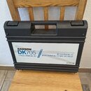 Černý plastový přepravní kufr s rukojetí a dvěma zámky. Na přední straně je bílá nálepka s nápisy SAMSON DK705 5-PIECE DRUM MIC KIT, Q71 KICK DRUM MI…