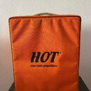 Oranžový textilní kryt na hudební zesilovač. Uprostřed je černý nápis HOT® a pod ním menší text true tube amplifiers. Kryt vykazuje mírné opotřebení…