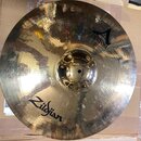 Zlatavý kovový činel s viditelným klepaním povrchu. Na čineli jsou černé nápisy Zildjian a A CUSTOM CRASH 18". Povrch je lesklý s několika drobnými o…