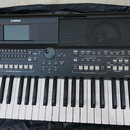 Černý digitální klavír značky YAMAHA s modelem PSR-SX600. Nástroj má bílé a černé klávesy, displej v horní části vlevo a mřížku reproduktoru vpravo.…