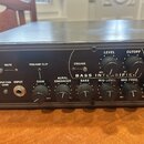 Černý rackový přístroj s nápisem BASS INTENSIFIER. Přední panel obsahuje ovládací prvky: přepínače MUTE, PREAMP CLIP a ENGAGE, vstup INPUT s přepínač…