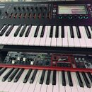 Dvě klávesové nástroje umístěné na stojanu nad sebou. Horní černý instrument nese v levém horním rohu logo Roland a vedle něj neúplný nápis ROM. Spod…