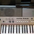 Šedý digitální klavír značky YAMAHA s integrovaným reproduktorem vlevo. Nástroj má bílé a černé klávesy a ovládací panel s mnoha tlačítky, posuvníky…