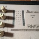 Detailní pohled na horní panel mixážního pultu značky Ibanez, model RM122. Na panelu je nápis 12CHANNEL STEREO MIXER, kontrolka POWER a dvě stupnice…