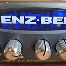 Detailní záběr na přední panel černého zesilovače s velkým modře podsvíceným nápisem GENZ-BENZ. Pod nápisem se nachází pět kovových knobů s rýhovaným…