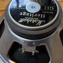 Kytarový reproduktor s kovovým rámem a černým magnetem. Na horní štítku jsou nápisy Marshall, Heritage AMPLIFICATION, G12, 8 Ω a CELESTION. Dále je z…