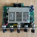 Fotografie zachycuje vnitřní elektroniku hudebního zařízení na zelené desce plošných spojů. V horní části je umístěn velký hliníkový chladič s vodoro…