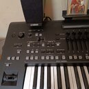 Černý digitální klavír značky YAMAHA s ovládacími prvky, tlačítky a displejem. V horní části je umístěn černý externí reproduktor. Na levé straně se…