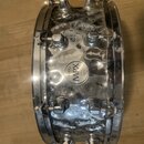 Stříbrný kovový snare drum s chromovaným povrchem. Uprostřed korpusu je kulatý štítek s nápisy MAPEX a MPX STEEL. Povrch nástroje vykazuje výrazné zn…