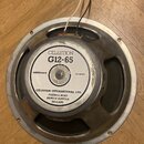 Kruhový reproduktor s kovovým rámem a magnetem. Na bílém štítku je uveden nápis CELESTION G12-65, IMPEDANCE 15 OHMS a adresa CELESTION INTERNATIONAL…