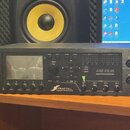 Černý rackový procesor s nápisem FRACTAL AUDIO SYSTEMS a označením AXE-FX III PREAMP/EFFECTS PROCESSOR. Zařízení má displej, několik ovládacích tlačí…