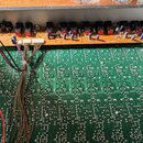 Fotografie zachicuje vnitřek elektronického zařízení s dvěma deskami plošných spojů. Horní oranžová deska obsahuje řadu černých přepínačů a několika…