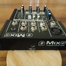 Černý kompaktní mixér s nápisem MIX5 5-CHANNEL COMPACT MIXER a logem stylizovaného běžce. Na zadní straně jsou viditelné vstupy a výstupy s označením…