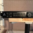 Černý rackový audio rozhraní s bílým logem APOGEE a symbolem „A“. Na předním panelu jsou vstupy označené jako IN, výstupy OUT (G1, G2) a sekce INPUT…