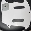 Bílá pickguard pro kytaru s dvěma oválnými výřezy. V levé horní části je nalepený čtvercový kovový nebo plastový platek s kulatým otvorem. Povrch je…