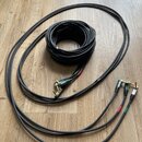 Černé audio kabely sviténované do klubku a rozprostřené na dřevěné podlaze. Konce kabelů mají zlaté konektory a jsou označeny červenými a zelenými kr…