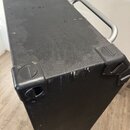 Černý reproduktorový box s texturovaným povrchem. Horní strana je vybavena kovovou rukojetí a čtyřmi plastovými rohovými chrániči. Na hraně v pravé č…
