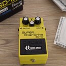 Žlutý kytarový efekt s nápisy SUPER Over Drive a SD-1w. Na spodní části je černé pole s logem BOSS a nápisem WAZA CRAFT doprovázeným japanským znakem…