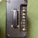 Kytarový kombo zesilovač v černém koženěném potahu s úchytem. Na ovládacím panelu jsou nápisy INPUT, GAIN, VOLUME, EQ, HT 1, EMULATED OUTPUT HEADPHON…