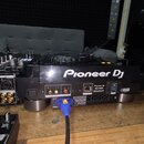 Zadní strana DJského přehrávače značky Pioneer DJ, model CDJ-3000. Zařízení je černé a má v zadní části různé konektory, včetně napájecího kabelu zap…