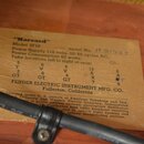 Fotografie detailu papírové štítku s technickými specifikacemi přilepeného na dřevěný povrch. Na štítku je uveden název "Harvard", Model 5F10 a Seria…