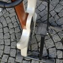 Fotografie zachicuje zadní část bílé elektrické kytary umístěné na černém stojanu. Viditelný je dřevěný hmatník a krk nástroje v hnědé barvě. Na zadn…