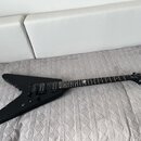 Černá elektrická kytara s tělem ve tvaru V. Na hlavě je bílé logo Epiphone a nápis Authorized Dealer. Hриф má v horní části bílou inlaidaci ve tvaru…