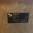 Fotografie zachycuje detail černého štítku s bílým textem na šedém, hrubém povrchu. Na štítku je logo a nápis Schneider, model 2264 LS a označení Lau…
