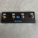 Černý obdélníkový kytarový spínací pedalboard s modrým okrajem. Na horní straně jsou čtyři stříbrné spínací tlačítka označená písmeny A, B, C a D. Up…
