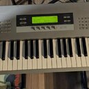 Stříbrný syntetizátor s klaviatura v bílé barvě. V pravém horním rohu je nápis KORG Z1 MULTI MODELING SYNTHESIZER. Přístroj obsahuje displej s žlutým…