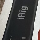 Černý obdélníkový přístroj s nápisy HD 2 a iRig. V horní části je modrá kontrolka, ve spodní části jsou dvě ikony znázorňující kytaru a zesilovač. Po…