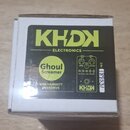 Bílá krabička s černým štítkem, na kterém je žlutý nápis KHDN ELECTRONICS. Štítek obsahuje název efektu Ghoul Screamer a text KIRK HAMMETT OVERDRIVE.…