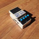 Bílý efekt pedál Digital Delay DD-8 s černým ovládacím panelem. Na horní části je nápis Digital Delay DD-8 a označení vstupů a výstupů: INPUT B, INPU…