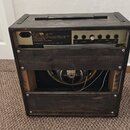 Zadní strana kytarového komba v tmavém dřevěném rámu. Na horním panelu jsou viditelné konektory a nápisy: RETURN, SEND, HEADPHONE a FOOTSWITCH. V lev…