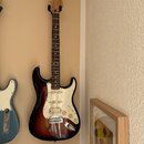 Elektrická kytara s tónem sunburst a bílým pickguardem. Na hlavě hředu je viditelné logo Fender. Nástroj má tři snímače, pětistupňový přepínač a tři…