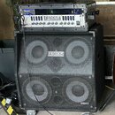 Fotografie zobrazuje basový zesilovač a reproduktorovou skříň v černém provedení. Na horním zařízení je nápis FENDER BASS AMPLIFICATION a pod ním ozn…