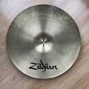 Kruhové činely z kovu s koncentrickým broušením povrchu. Na spodní části je černý nápis Zildjian. Povrch vykazuje mírné známky opotřebení a nečistoty.
