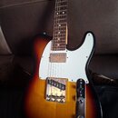 Elektrická kytara s tónem sunburst a bílým pickguardem. Má hnedý hmatník s bílými tečkovými značkami a kovový ovládací panel. Na spodní části těla je…