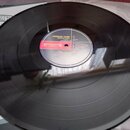 Černá vinylová deska s bílým středovým štítkem. Na štítku je uveden název kapely CRIMSON GLORY a vydavatel ROADRUNNER. Jsou zde viditelné názvy sklad…