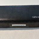 Černý obdélníkový kufr z texturovaného materiálu připomínajícího kůži. Na horní části je bílé logo a nápis SENNHEISER. Na boční straně se nachází bíl…