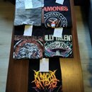 Pět černých a šedých triček s potisky rozložených na hnědém stole. Na tričkách jsou viditelné nápisy AMONES, JOHNNY JOEY, BEASTIMBLAG, LLY TALENT a C…