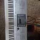 Stříbrný digitální klavír s integrovanými reproduktory. Na ovládacím panelu je vidět logo YAMAHA a v pravém dolním rohu nápis PSR-S710. Nástroj vykaz…