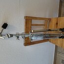 Kromě dřevěné židle je na fotografii vidět chromovaný kovový stojan s černým plastovým knoflíkem v horní části. Na středovém sloupku je viditelný náp…