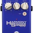 Modrý efekt pedál s nápisem HARMONY SINGER a logem TC-HELICON. Na horní straně jsou tři bílé otočné oválné knoflíky s popisky Harmony, Level a Reverb…