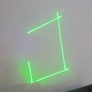 Fotografie zobrazuje zelený laserový paprsek promítaný na bílou stěnu. Laser tvoří dvě kolmé linie, které spolu svírají pravý úhel. Žádné značky ani…