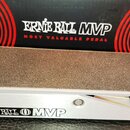 Kytarový pedál s hliníkovým šasi a hrubou, protiskluzovou povrchovou úpravou na horní části. Na boku je uveden nápis ERNIE BALL MVP. V pozadí je vidě…