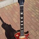 Elektrická kytara s tónem sunburst, vybavená dvěma humbuckery a čtyřmi ovládacími knoflíky. Na hlavě je bílý nápis Gibson a zlatý nápis Les Paul MODE…