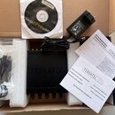 V kartónové krabici s polystyrenovými vložkami se nachází černé zařízení s nápisem TERRATEC. Součástí je napájecí adaptér, USB kabel v plastovém sáčk…