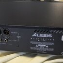 Zadní strana černého elektronického zařízení značky ALESIS, model MASTERLINK ML 999. Jsou zde vidět analogové vstupy a výstupy (jack a XLR), digitáln…